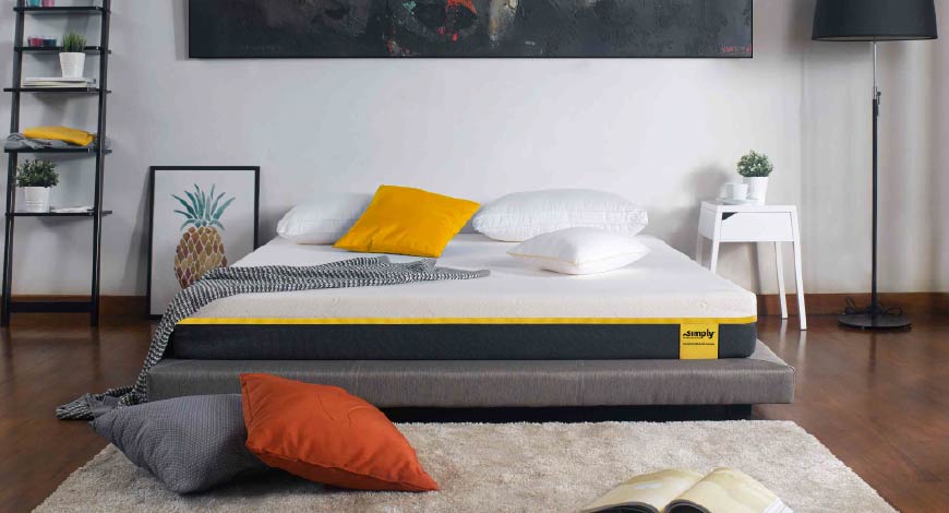 kasur busa Simply Bed dengan bantal putih, kuning, oranye, dan abu-abu di dalam ruangan estetik